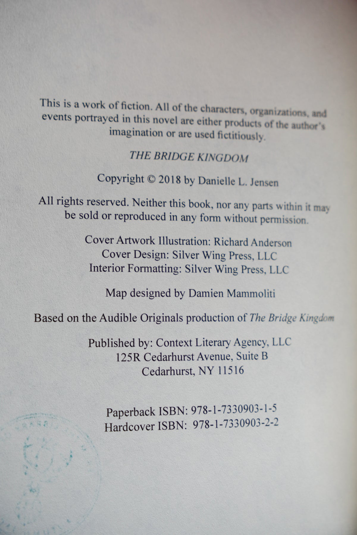 The Bridge Kingdom and The Traitor Queen — original-cover paperback pair: Bridge Kingdom copyright page and ownership stamp transfer; actual copy